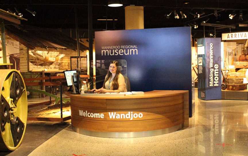 Reception desk of wanneroo regional museum with attendant sitting at reception desk smiling invitingly.