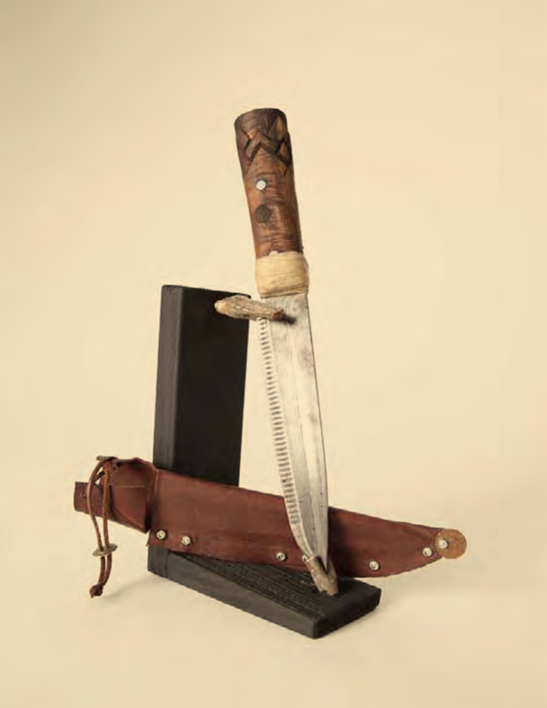 A handmade knife is displayed artistically with its sheath