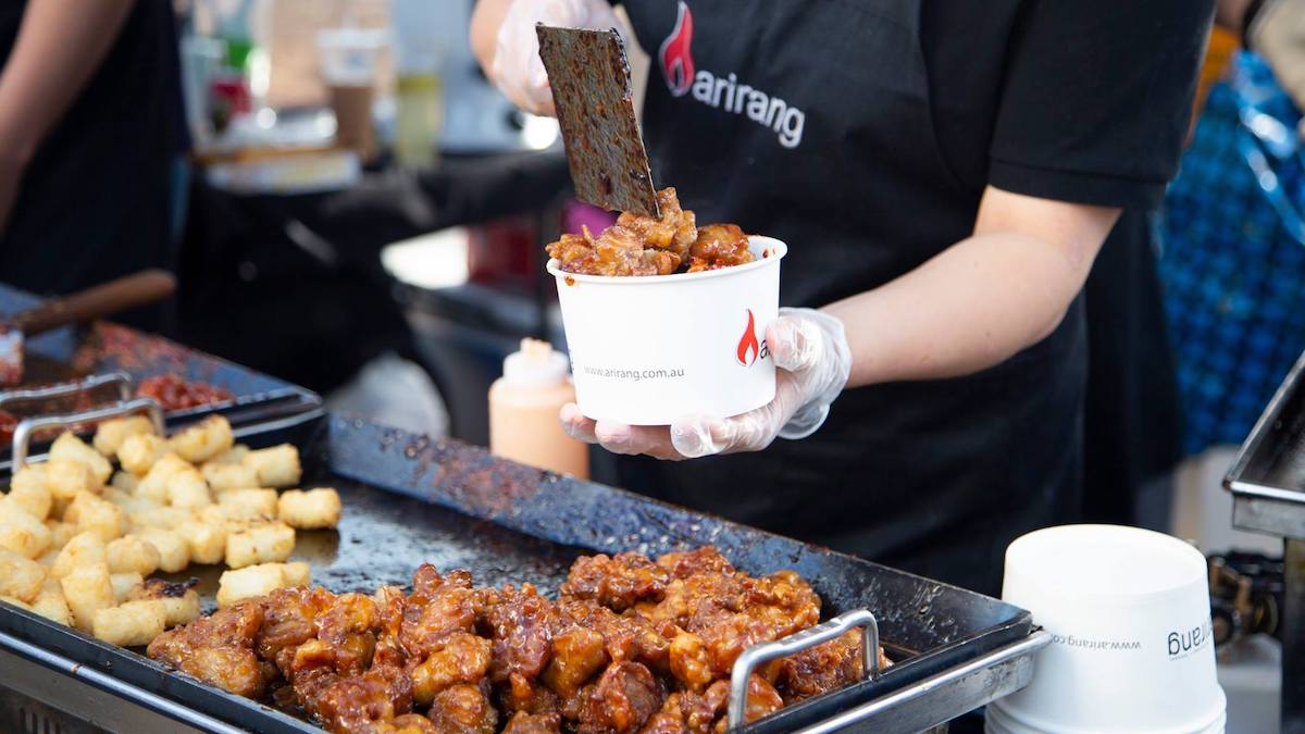 Street-food vendor cooking at a hawkers market serving Korean fried chicken and potato.