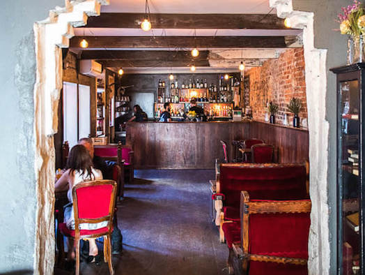 bar with red velvet chairs and intricate archway